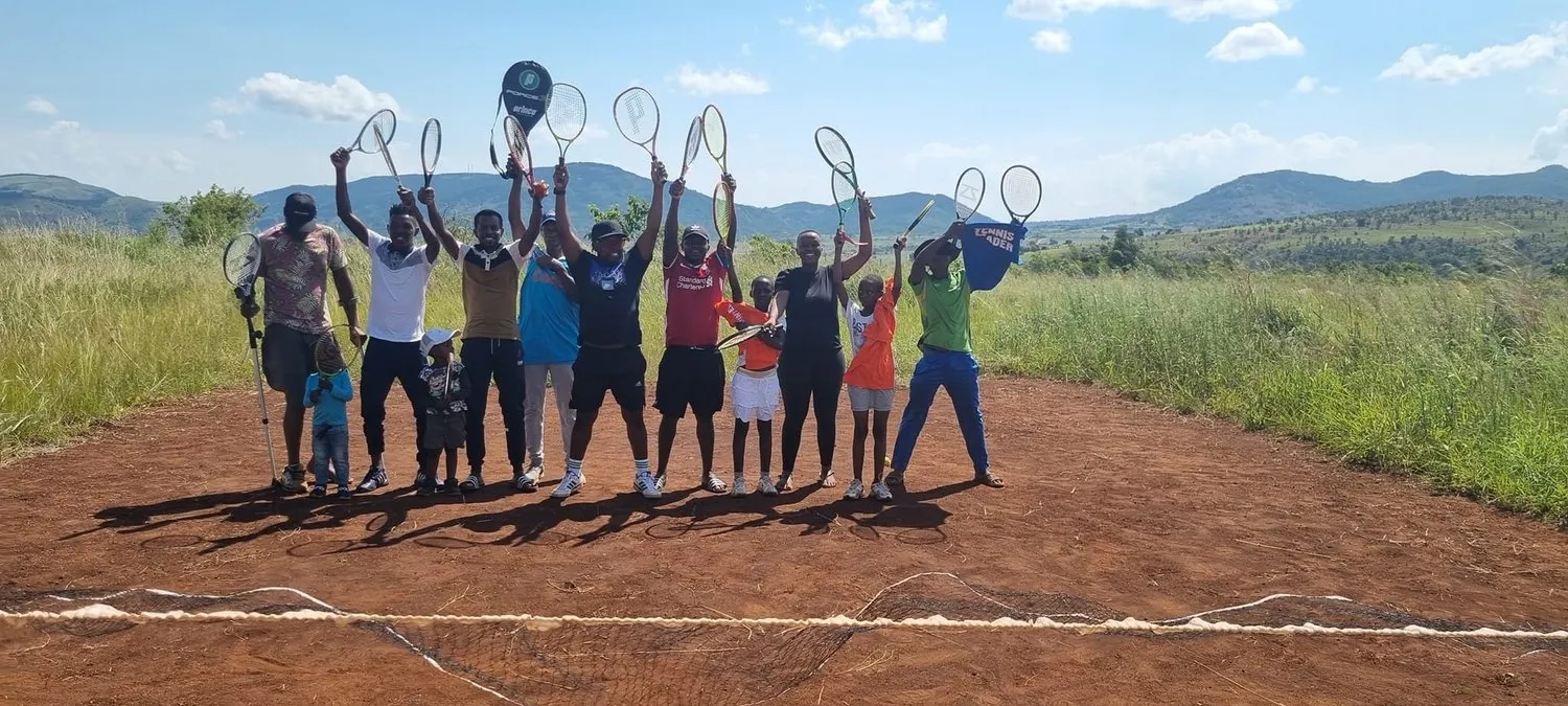 Children raising their rackets on a dirt court