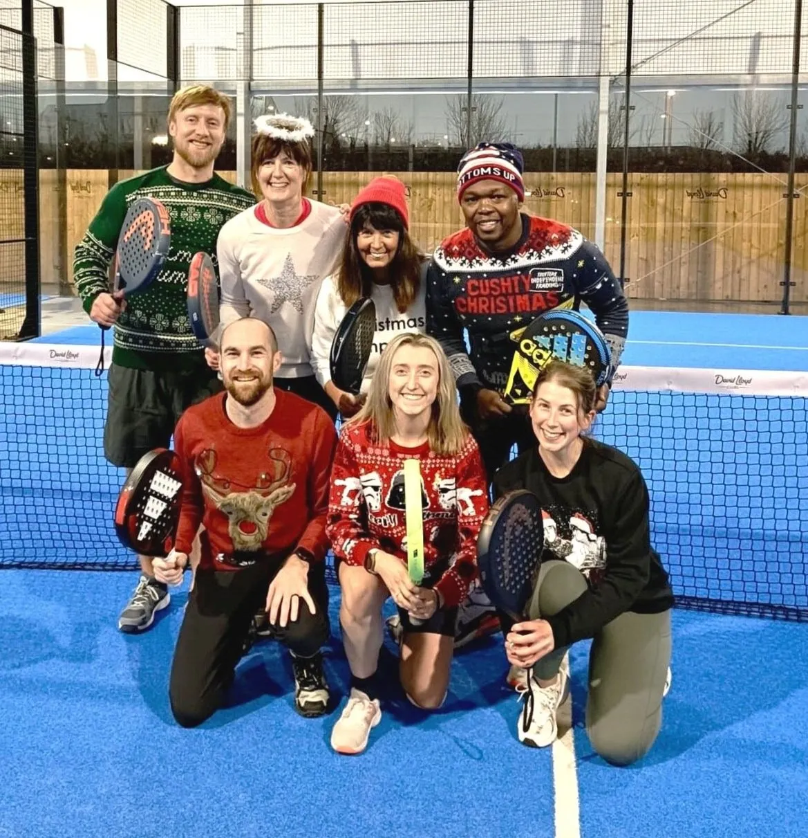 Padel players in festive jumpers on court